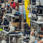 Garment workers seated at sewing machines in a busy factor