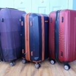 Three scuffed pink and purple suitcases.