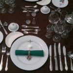 Formal dinner table setting with crockery and cutlery.